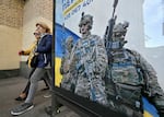 Pedestrians in Kyiv walk past a poster depicting Ukrainian servicemen and a slogan that reads, "Bring the victory soon," on Oct. 31.