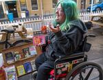 Jennifer Bradford laughs at her choice of books while visiting the Street Books library. Street Books is a small lending library built on a bike, that serves people experiencing homelessness. 