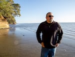A man standing on a beach around sunset.