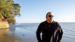 A man standing on a beach around sunset.