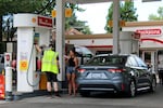 A gas station attendant helps a driver fill up their tank at a gas station in Portland, Ore., Aug. 4, 2023.