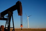 FILE - Pumpjacks operate in the foreground while a wind turbines at the Buckeye Wind Energy wind farm rise in the distance Monday, Sept. 30, 2024, near Hays, Kan.