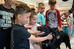 Freetown Elementary School students Mason Santos, left, and Mila Talbot, right, pet Hunter the dog after she finishes checking a classroom.