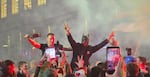 Crowds of people celebrate in the streets of Belgrade, Serbia, on Sunday night following the country's parliamentary election results. People are holding up their hands in celebration, and some people are holding up their smartphones to record the events.