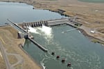 Water passes through a hydroelectric dam that spans the width of a river.