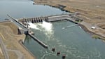 Water passes through a hydroelectric dam that spans the width of a river.