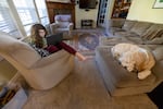 Mina Mohandessi, left, completes her virtual schoolwork as her dog Watson rests nearby, at their home in Vancouver, Wash., March 12, 2021.