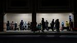 people stand in line at night in front of a building