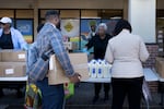 People receive food for furloughed federal workers at No Limits Outreach Ministries on October 21, 2025 in Hyattsville, Md. The US government shutdown dragged into a third week, with Congress gridlocked in a clash over spending and no resolution in sight to a crisis that has already cost thousands of jobs.