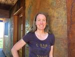 Amy Snover, director of the Climate Impacts Group at the University of Washington, stands outside her family’s cabin in Pine Forest. She replaced the wood siding on the house with metal siding to improve fire resistance and participated in community tree-thinning efforts.