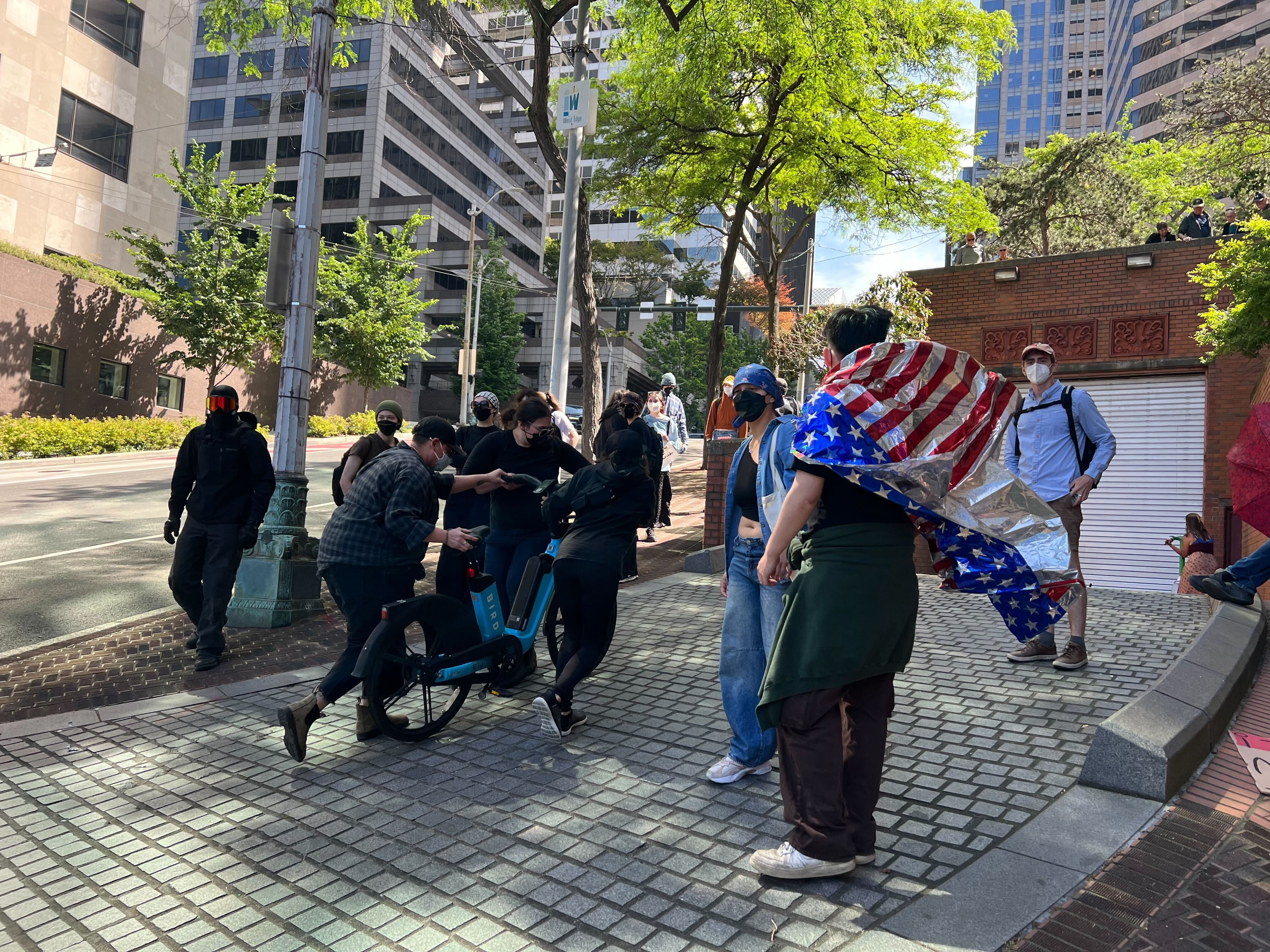 Protesters use e-bikes to block the vehicle exits from the Henry M. Jackson Federal Building on June 10, 2025, hoping to stop trucks carrying detained immigrants from leaving.