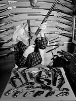 C.J. Hurst of West Covina, Calif., holds up a .44-caliber rimfire Model 66 Winchester rifle as he poses with his collection of about 600 antique guns in 1952.