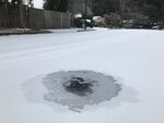 Ice is seen over a sewage grate on a residential road.
