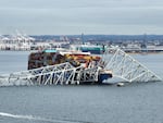 A steel frame from the collapsed Francis Scott Key bridge in Baltimore covers the top of the Dali ship. The container ship crashed into the bridge on Tuesday.