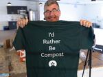 Return Home CEO Micah Truman holds up a T-shirt with a lighthearted slogan ("I'd rather be compost") during a tour of the Return Home funeral home, which specializes in human composting, in Auburn, Wash., on March 14, 2022. Washington in 2019 became the first state in the U.S. to make it a legal alternative to cremation.