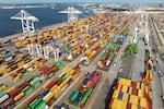 An aerial view of colorful shipping containers at the Port of Baltimore. There are container cranes along the edge of the water.
