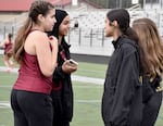 Three teenagers talk in tracksuits