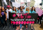 Women march against sexual assault and harassment with a #MeToo sign held in front.