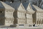 A person takes photos of a scene of frozen houses in the waterfront community of Crystal Beach in Fort Erie, Ontario, Canada.