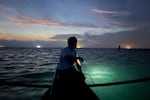 Resident Rolly Dela Cruz, getting ready to go spearfishing off the coast of Thitu Island. On the horizon, several Chinese fishing boats are floating, using bright lights to attract fish.