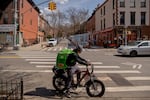 An Uber Eats delivery courier rides an electric bicycle through the Park Slope neighborhood of the Brooklyn borough of New York.