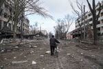 A man walks with a bicycle in a street damaged by shelling.