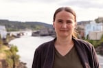 A portrait of a woman with a river and some buildings in the background.