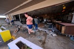 FILE - Kegan Ward, assistant manager of Swami Spirits, walks through debris of the damaged store in the aftermath of Hurricane Helene, in Cedar Key, Fla., on Sept. 27, 2024.