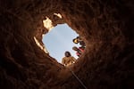 Members of an illegal diamond mining collective look down a mineshaft at the Nuttabooi mine.