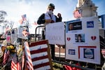 Anne Seymour, wearing a face mask, stands next to handmade signs for a memorial honoring U.S. Capitol Police Officer Brian Sicknick. Signs read "R.I.P. Officer Sicknick" and "#Hero."