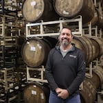 Matt Van Wyk stands in front of barrels that are aging an imperial milk stout.