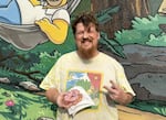 Josh Matthews of Springfield poses next to the Simpsons mural, with a "Homer" donut.