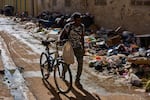 A man pushes his bicycle along a trash-strewn street in Havana, Cuba, Tuesday, June 9, 2026.