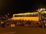 Protestors surround the ICE detention bus to sit down shortly before federal agents arrive.