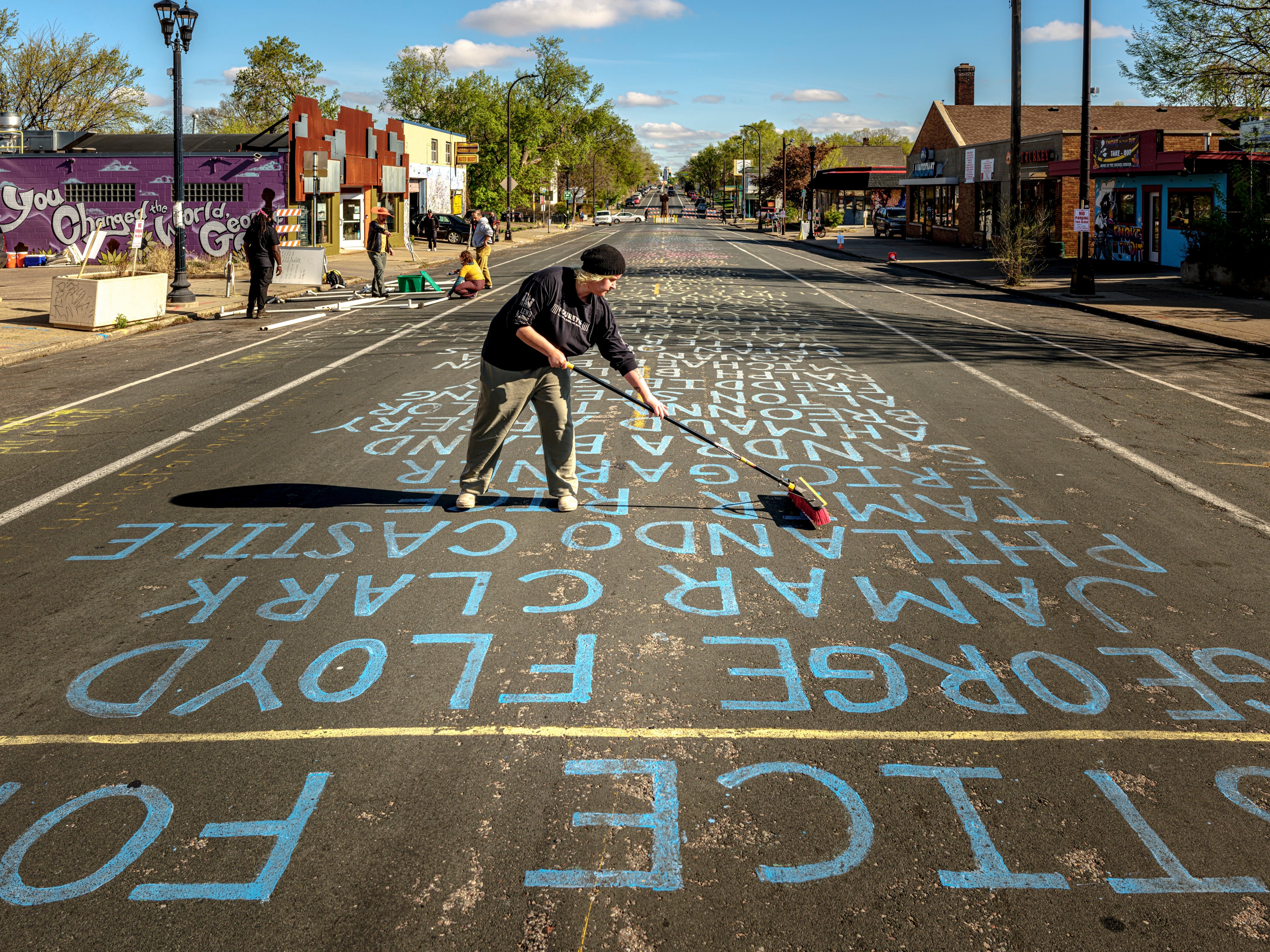 At George Floyd Square, a volunteer tends to the street where the names of people killed by police violence are painted.