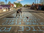 At George Floyd Square, a volunteer tends to the street where the names of people killed by police violence are painted.