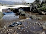 A bulldozer moves debris as a vehicle sits stranded in flooded water on U.S. Highway 101 in Montecito, Calif., Jan. 10, 2018.