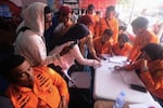 People look for the names of their family members on a passenger list after a ferry overturned in bad weather in the Java Sea, at the rescuers command center in Banjarmasin, South Kalimantan, Indonesia, Sunday, Sept. 13, 2026.
