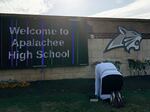 A person kneels in front of flowers placed outside the entrance to Apalachee High School on Thursday, a day after a mass shooting at the school in Winder, Ga.