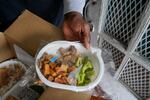 Jackie Robinson shows the contents of meal boxes he received that were delivered by Revolution Foods in New Orleans on Thursday, Feb. 11, 2021. Robinson, a 66-year-old retired cook who once worked at a French Quarter restaurant in New Orleans, struggled to get by on his Social Security benefits before the pandemic, occasionally visiting a food pantry. But over the summer he signed up for a city-run delivery program and now gets two meals a day, seven days a week. "Things were getting kind of tough, a little rough and ... I needed a little extra assistance," he said.