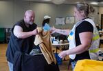 Dana Nichols gives a shirt to Dewey Iverson at the emergency cooling center at Multnomah Count East Building in Gresham, Ore.. on June 15, 2026. The shelter has snacks, drinks, as well as clothing items like flip flops and shirts available for visitors.