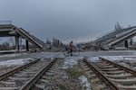 Destroyed bridge on the entrance to Pokrovsk from East direction and man pulling stuff on the bicycle in the front.