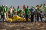 FILE - Workers collect debris on March 12, 2019 at the scene where an Ethiopian Airlines Boeing 737 Max 8 crashed shortly after takeoff, killing all 157 on board, near Bishoftu, or Debre Zeit, south of Addis Ababa, in Ethiopia. On Sunday, July 7, 2024, the Justice Department said Boeing has agreed to plead guilty to a criminal fraud charge stemming from two deadly crashes of 737 Max jetliners.