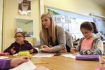 Teacher Michelle Moran, center, helps students with problems during small group work in a late-March class.