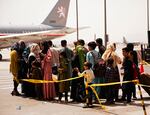 People line up on tarmac and wait to board an airplane.