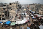 People walk past stalls selling goods amid the rubble of buildings destroyed during previous Israeli strikes, in Khan Yunis in the southern Gaza Strip on January 15, 2025.