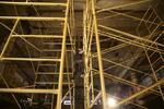 Artist Avantika Bawa scales "Mineral Spirit", the golden scaffolding that she spray painted and constructed in the Astor Hotel in Astoria for the biennial.