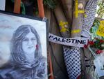 Yellow tape marks bullet holes on a tree and a portrait and flowers create a makeshift memorial, at the site where Palestinian-American Al-Jazeera journalist Shireen Abu Akleh was shot and killed in the West Bank city of Jenin in May.