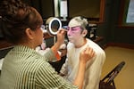 Yat Sing Music Club member Eva Siew Hop Fan, right, receives assistance from a cosmetician while applying makeup for the role of Co Wan in the Cantonese opera "Handsome Pun On," at the Portland Chinatown Museum in Portland, Ore., on Aug. 24, 2024.