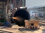 In this undated photo provided by the EPA, a crew member uses a plasma torch to dismantle one of the retorts left on the J.H. Baxter site in Eugene. The U.S. government alleges that the retorts were used improperly to evaporate toxic wastewater into the air in 2019, violating federal environmental law.